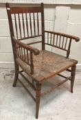 A late 19th Century stained beech framed rush seat spindle back Sussex type armchair after the