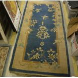 A Chinese carpet, the central panel set with floral motifs on a blue ground,