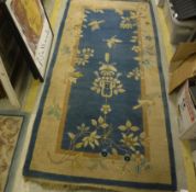 A Chinese carpet, the central panel set with floral motifs on a blue ground,