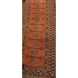 A modern Persian runner with repeating medallions on a rust ground,