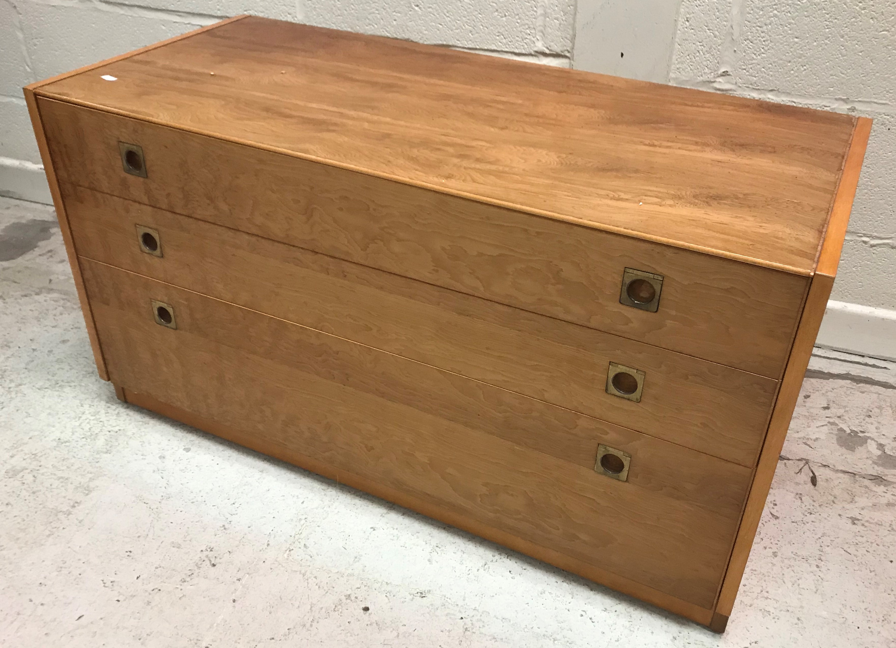 A 1960's yew wood chest of three long graduated drawers with brass flush handles,