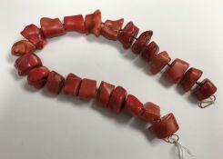 A rough cut red or pink dyed coral section necklace of 23 various beads with 9 carat gold clasp,