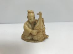 A Japanese Meiji Period netsuke as a seated lute-player (unsigned)