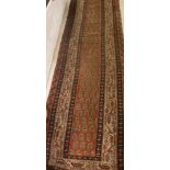 An early 20th Century Persian runner with all-over stylised leaf / hook motif decoration on a red