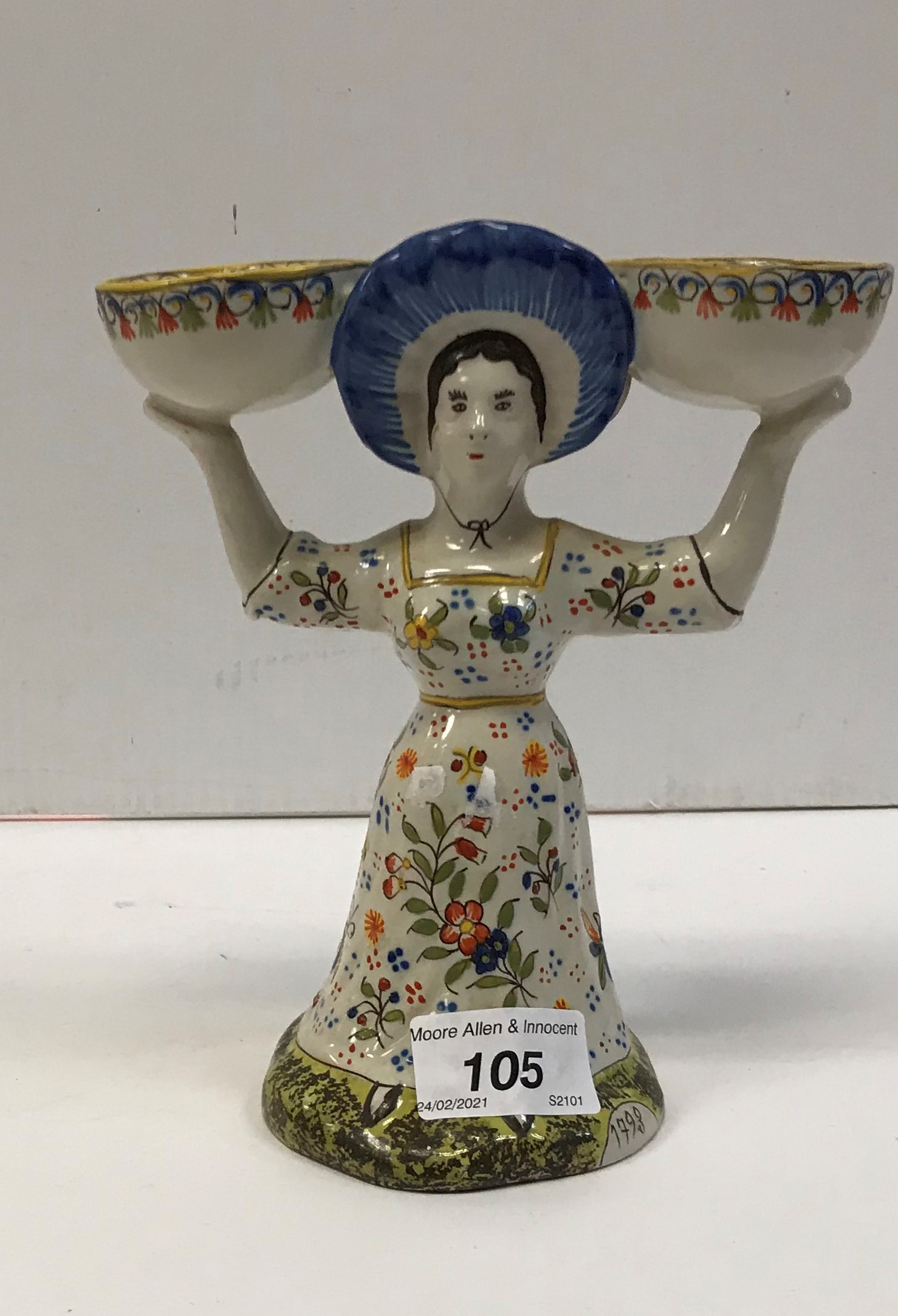 A faience salt in the form of a lady carrying two bowls,