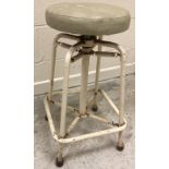 A 1950's Cowtan & Cox wrought iron framed adjustable stool on sprung pedestal to splayed legs