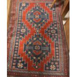 A Caucasian rug, the central panel set with repeating diamond medallions on a red and blue ground,