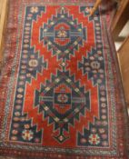 A Caucasian rug, the central panel set with repeating diamond medallions on a red and blue ground,