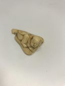 A Japanese Meiji Period carved ivory netsuke as a man upon a palm leaf,