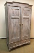 A French pine armoire with two cupboard doors enclosing a hanging space over two drawers,