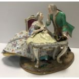 A 19th Century Meissen figure group of a gallant and lady at a sewing table, his hat upon the table,