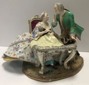 A 19th Century Meissen figure group of a gallant and lady at a sewing table, his hat upon the table,