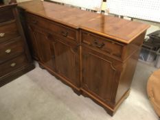 A modern yew wood and cross banded break front sideboard with central long drawer over two cupboard