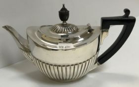 A Victorian silver oval teapot with semi-reeded decoration, ebony finial and ebonised handle,