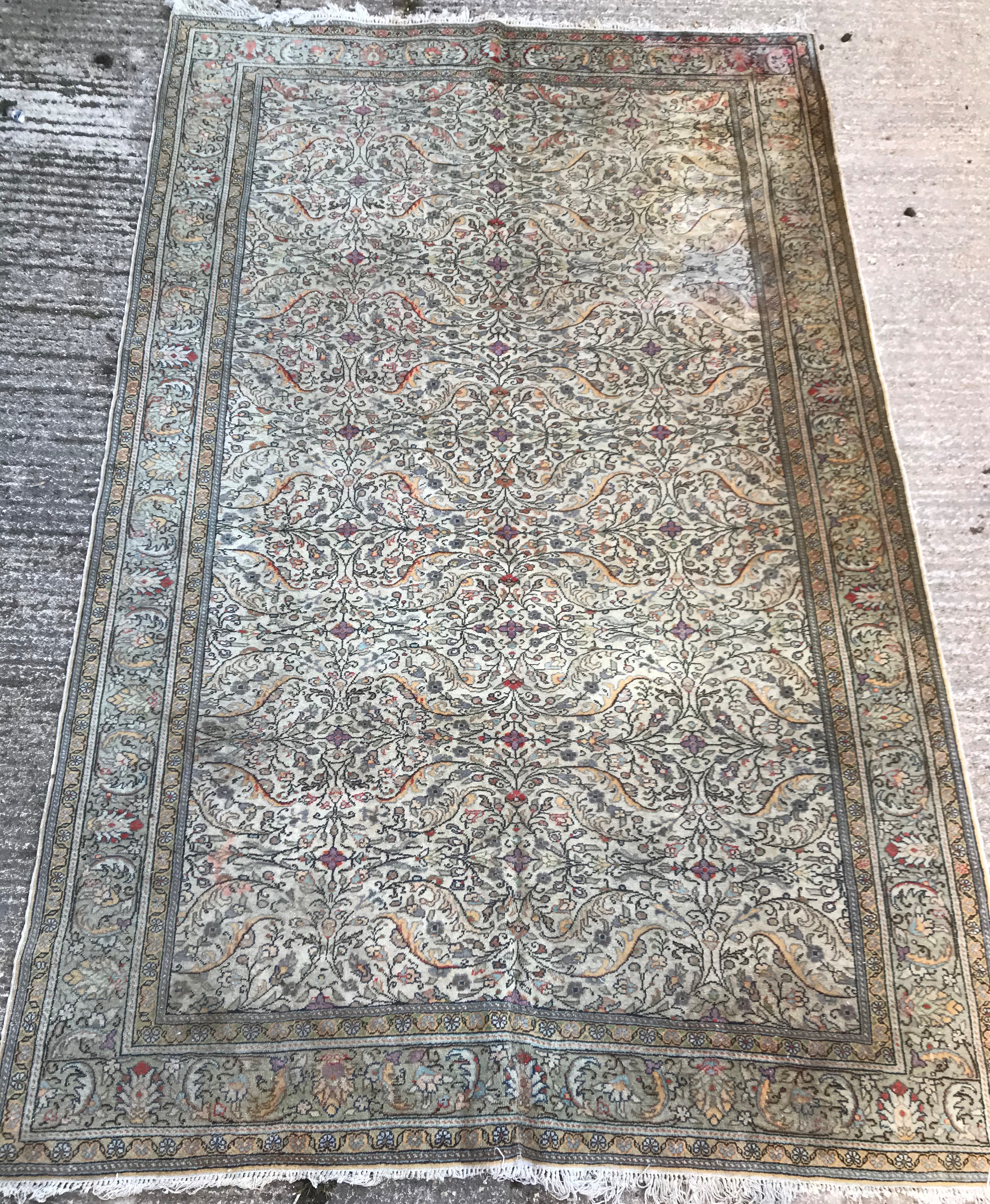 An Oriental carpet, the central panel set with all over floral decoration on a fawn ground,