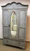 A painted and gilded single mirror door wardrobe with single drawer, raised on bracket feet,