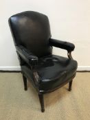 A Victorian walnut framed open arm chair, the black leatherette back,