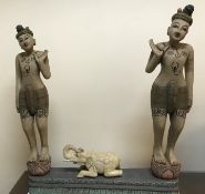 A carved and painted Indonesian gong stand as two figures, their hands raised, flanking an elephant,
