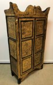 A modern Indonesian black and gold lacquered two-door wardrobe decorated with figural panels, 88.