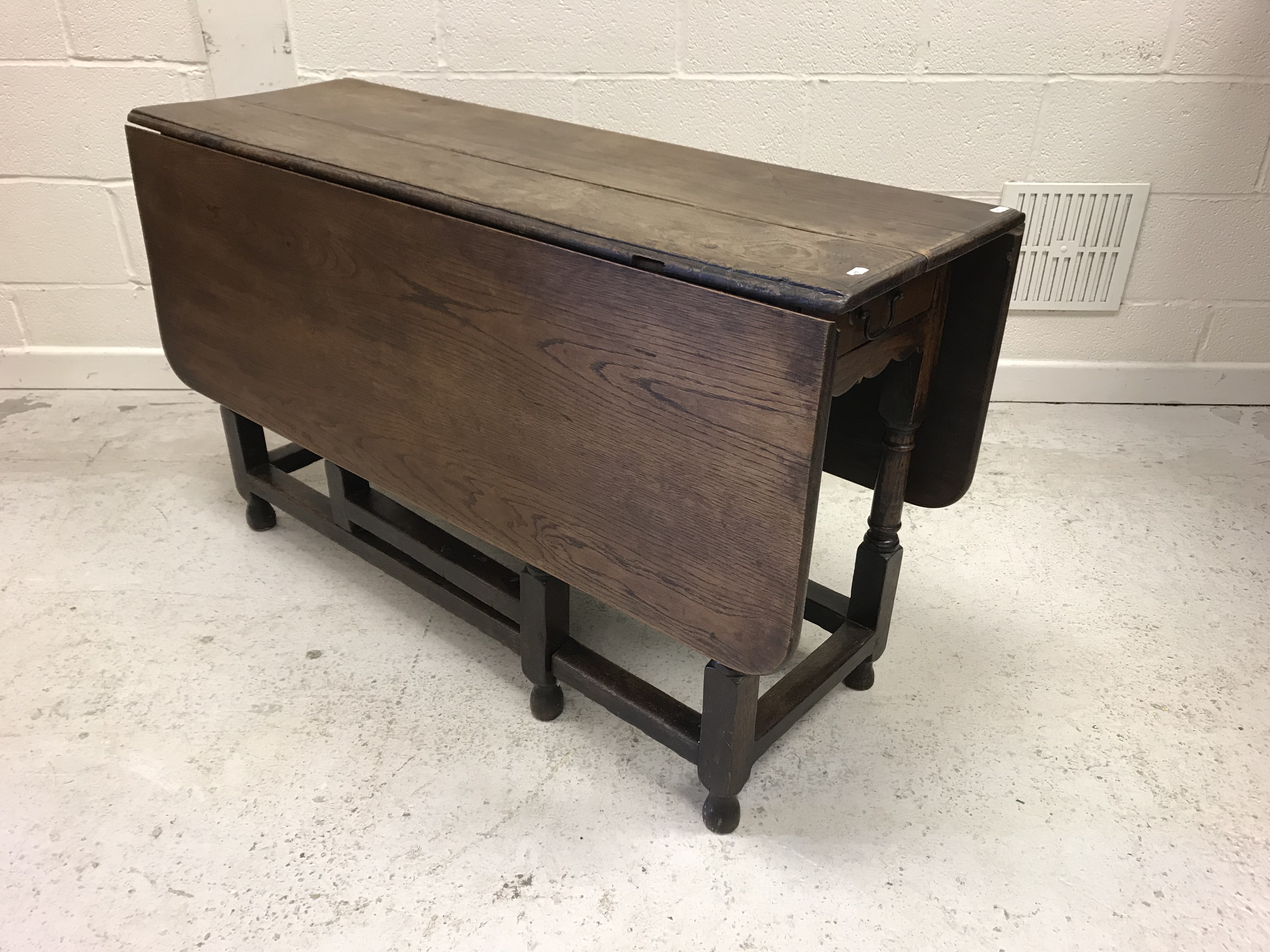 A 20th Century oak rectangular drop-leaf gate-leg dining table with single end drawer in the 18th
