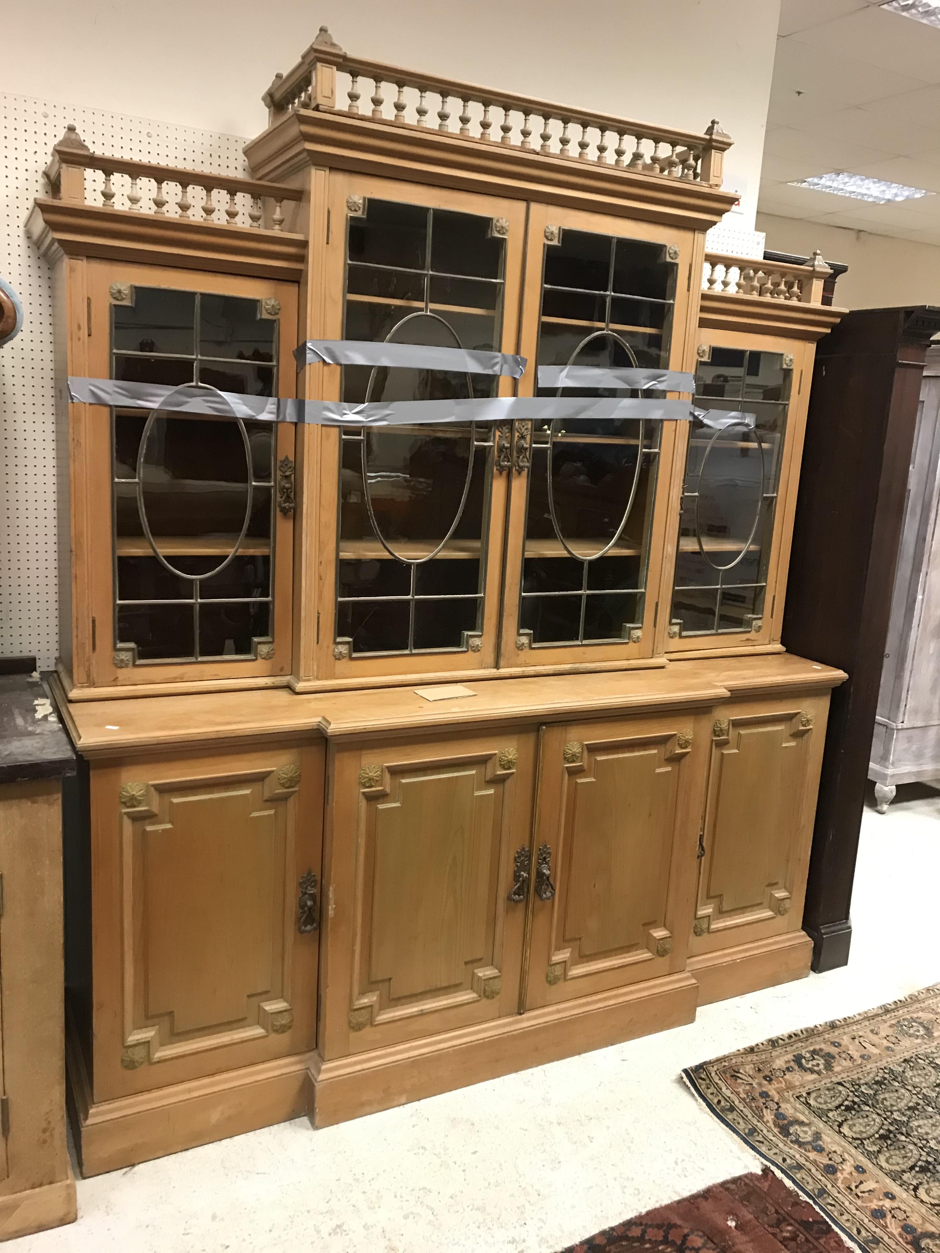 A pine breakfront bookcase cabinet in the George III style with galleried cornice over four glazed