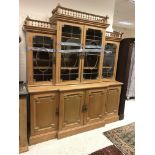 A pine breakfront bookcase cabinet in the George III style with galleried cornice over four glazed