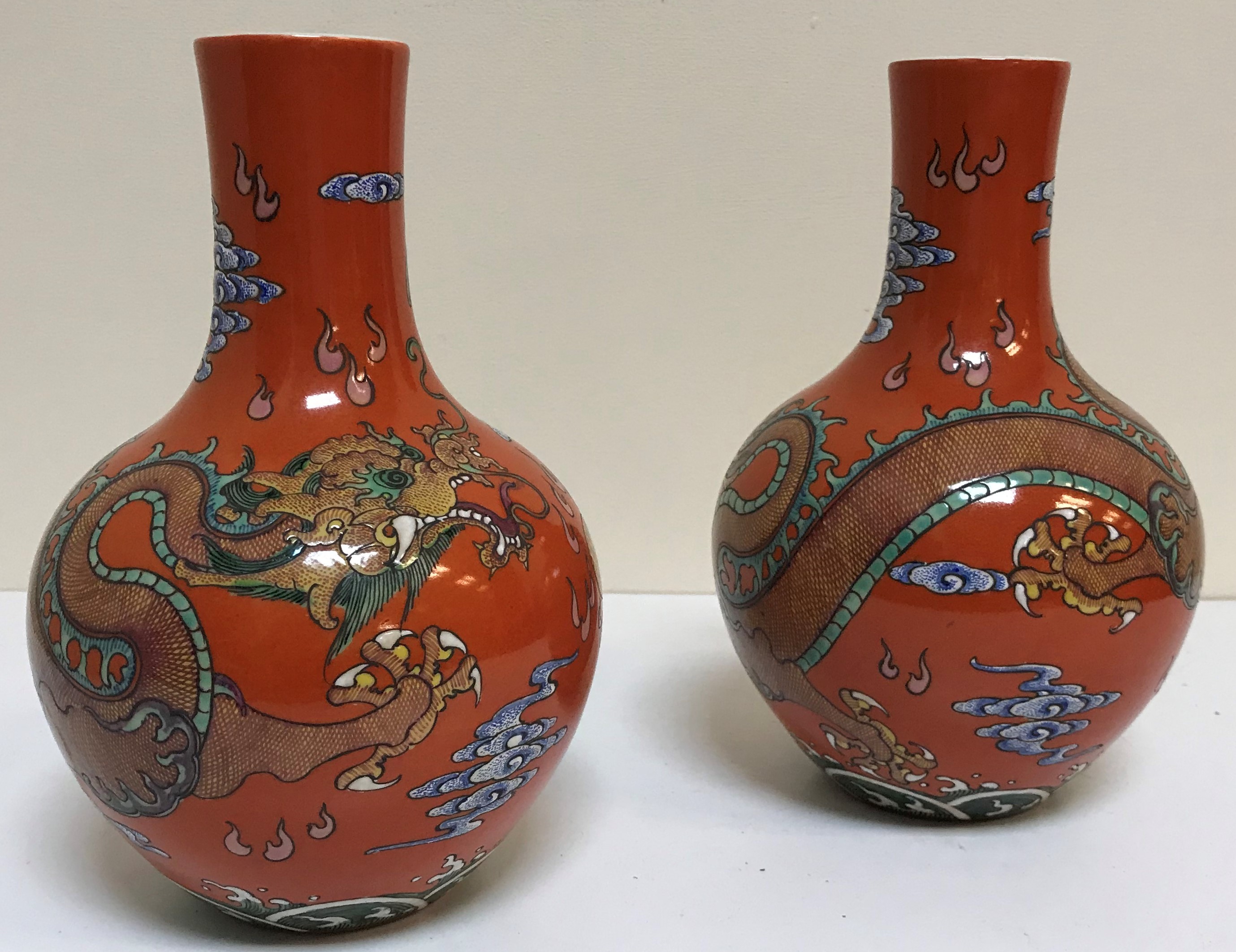 A pair of circa 1900 Chinese oxide red ground five toed dragon decorated vases bearing blue