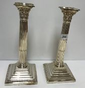 A pair of late Victorian Corinthian silver column table candlesticks on stepped square bases with