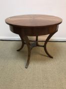 A modern walnut veneered circular centre table in the Empire taste on four splayed supports,