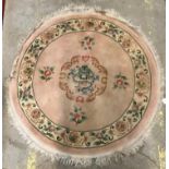 A Chinese rug, the pale pink ground set with floral sprays and central dragon head motif,