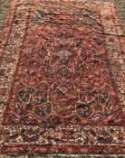 A Persian rug with centre medallion on a red ground and all over floral decoration within a cream