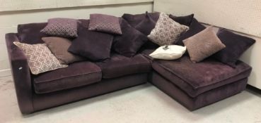 A modern purple upholstered three seat sofa with day bed end and various cushions,