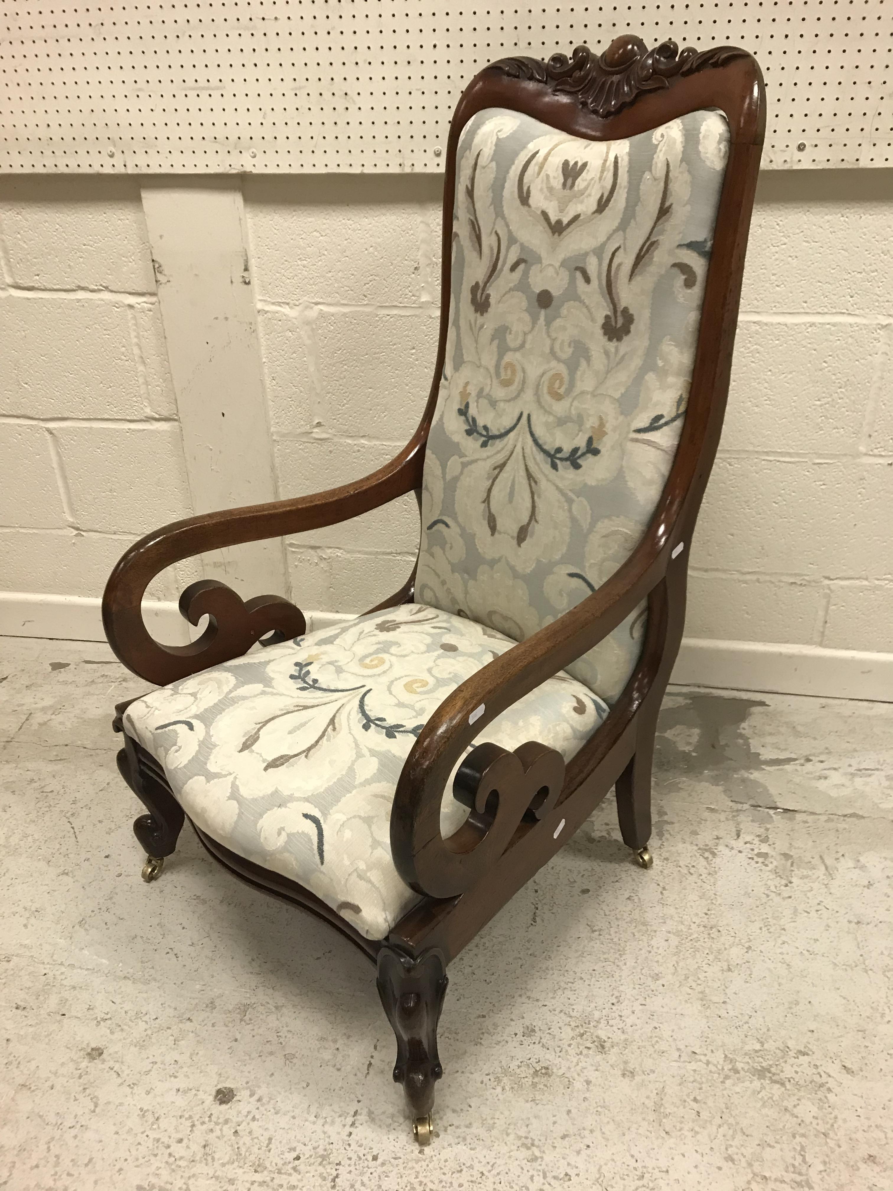 A Victorian mahogany framed scroll arm chair with foliate carved top rail over an upholstered back