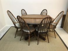 An Ercol elm D end dining table, the top with extra leaf raised on a quatrefoil pedestal base,