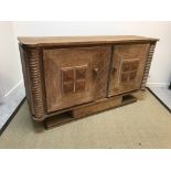 A 20th Century oak two-door sideboard with square panelled doors on centre pedestal base,