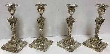 A pair of late Victorian silver sheathed table candlesticks with embossed ram's head,