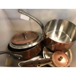 A box containing various copper pans and skillets, jelly moulds,