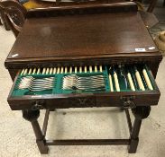 A 1930s oak cased canteen table in the gothic revival taste containing an eight place canteen of