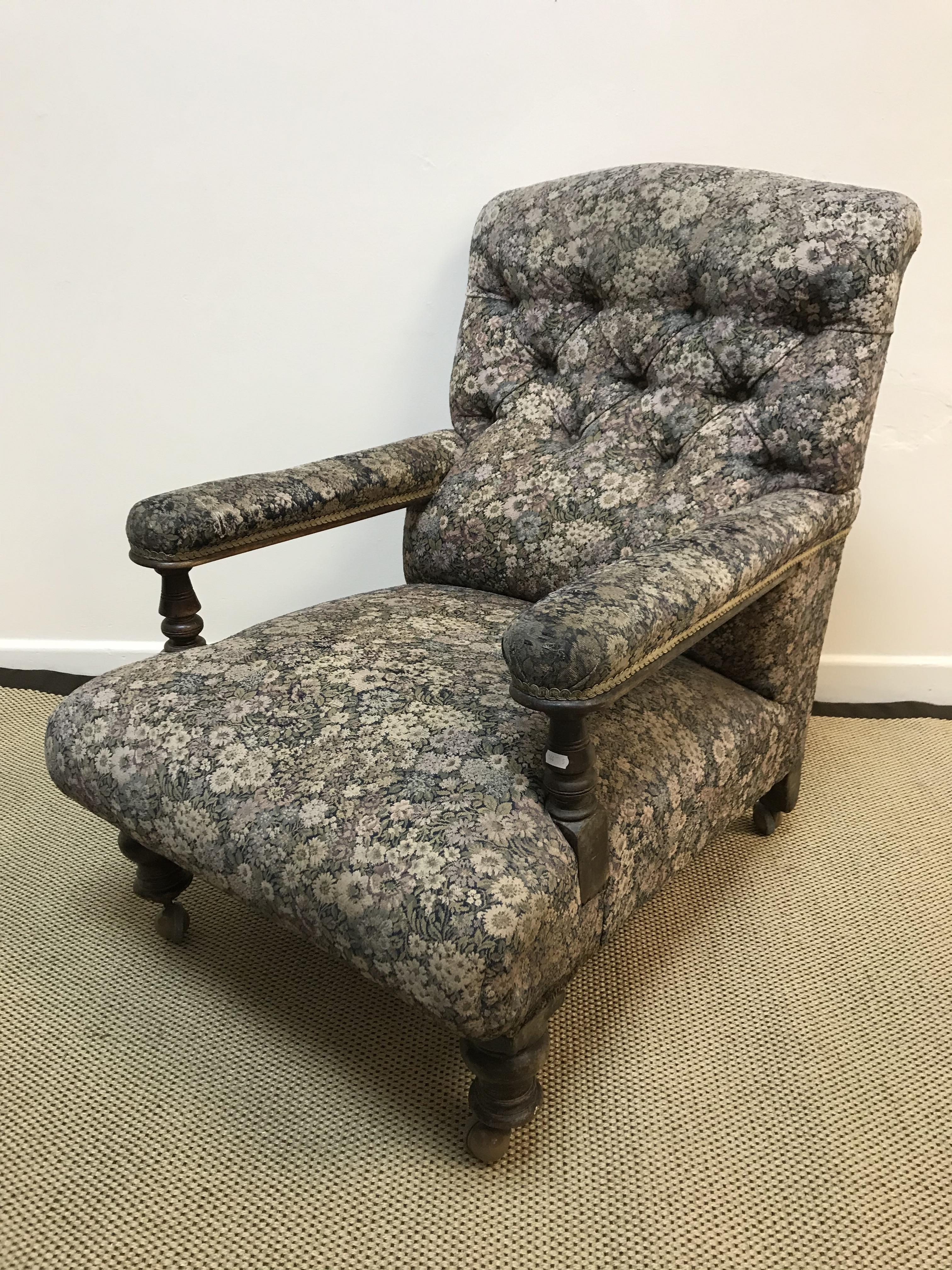A Victorian button back upholstered open arm oak framed armchair on turned legs to later castors,