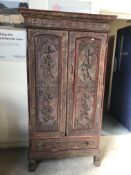 A 20th Century Indonesian relief-work decorated two-door cupboard with drawer on scroll feet (with