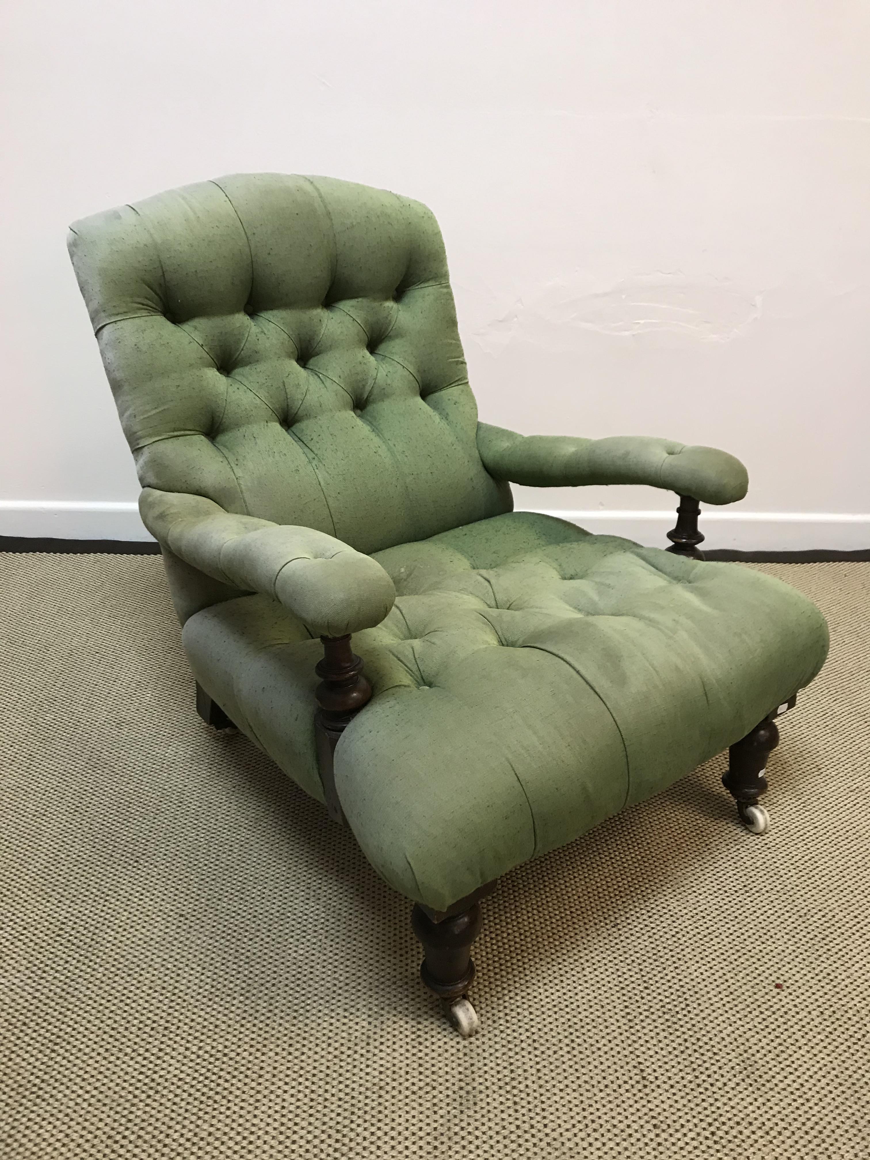 A Victorian green buttoned upholstered open arm chair on turned legs to castors,