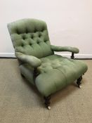 A Victorian green buttoned upholstered open arm chair on turned legs to castors,