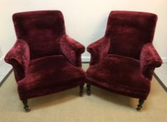 A pair of circa 1900 burgundy velour upholstered scroll arm chairs on ebonised baluster-turned