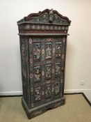 A 20th Century Indonesian painted and carved wooden single door cupboard with all over figural