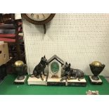 A 1930s marble and onyx cased clock garniture as a dog kennel flanked by two hounds, one seated,