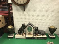 A 1930s marble and onyx cased clock garniture as a dog kennel flanked by two hounds, one seated,