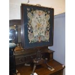An early 19th Century mahogany framed needlework tapestry panelled adjustable fire screen with