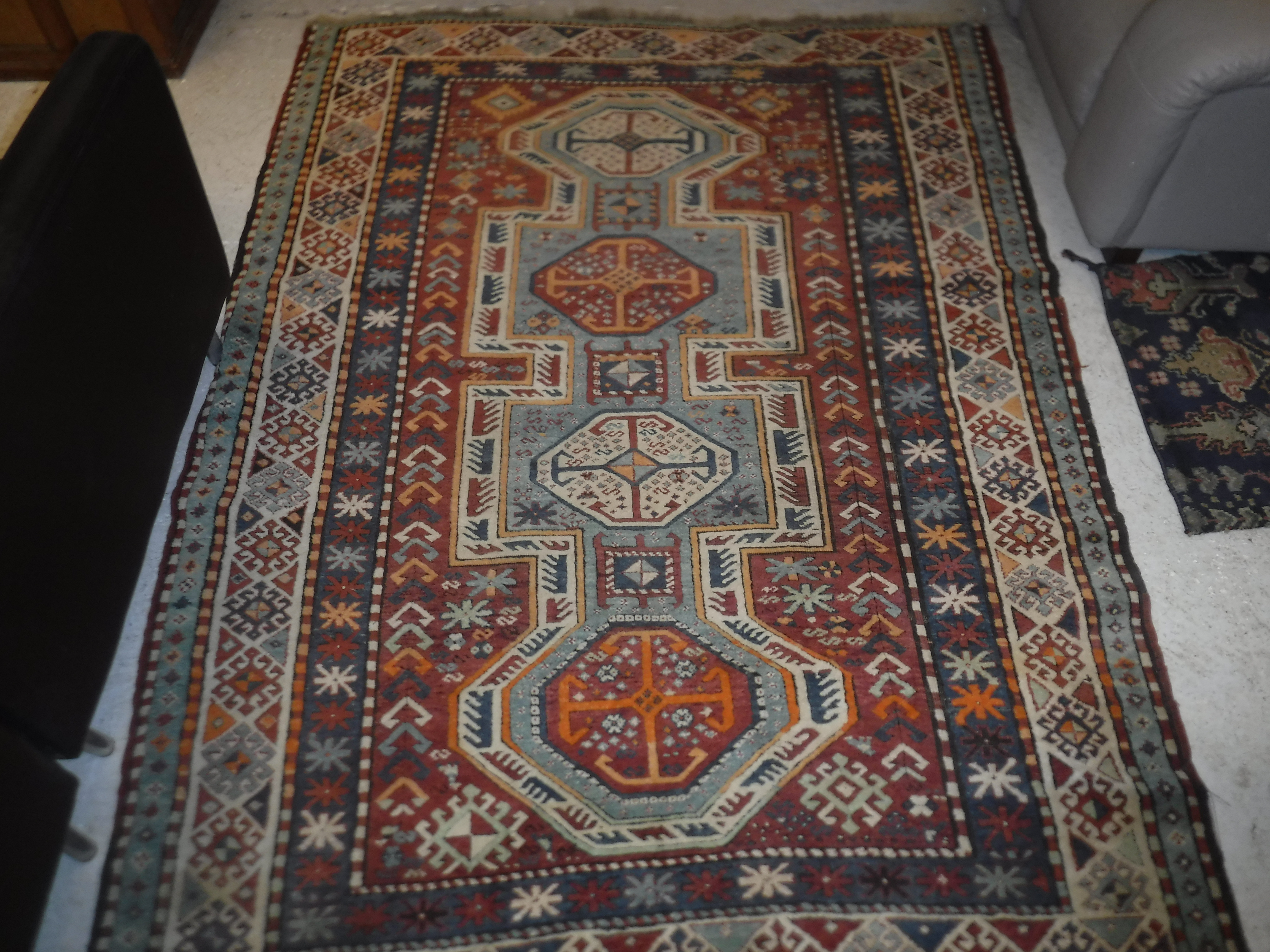 A Kazak carpet, the central panel set with repeating medallions on a mint green ground,