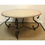 A modern circular dining table, the painted top raised on a painted metal scrolling base,