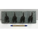 A set of four coat hooks as dogs' tails, mounted as one,